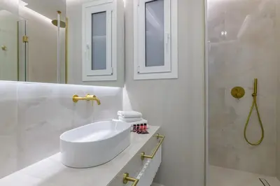 a white bathroom with a sink and a shower at Apollo - Luxenia Suites in Athens