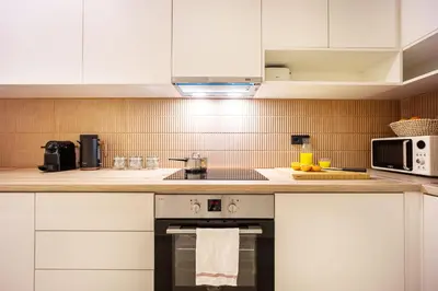 a kitchen with white cabinets and a stove top oven at Spacious 2BR in Koukaki l Balcony l Near Acropolis in Athens