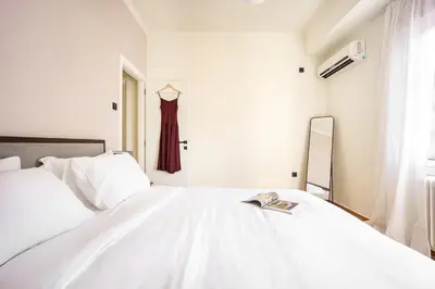a white bedroom with a bed and a mirror at Spacious 2BR in Koukaki l Balcony l Near Acropolis in Athens
