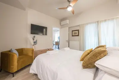 a bedroom with two beds and a chair at Marina Zeas Comfy Apartment in Piraeus