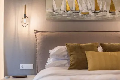 a bed with pillows and a painting on the wall at Marina Zeas Comfy Apartment in Piraeus