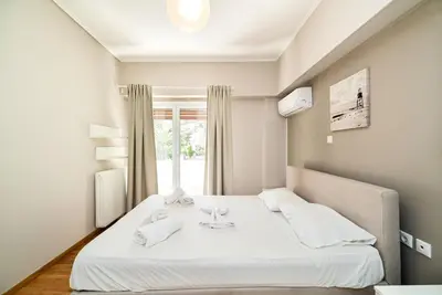 a white bed in a room with a window at The Faliro Oasis in Athens