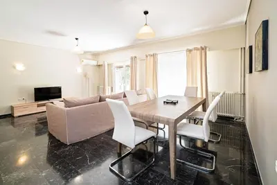 a living room with a couch and a table and chairs at The Faliro Oasis in Athens