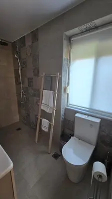 a bathroom with a toilet and a shower and a window at Maria guesthouse in Spáta