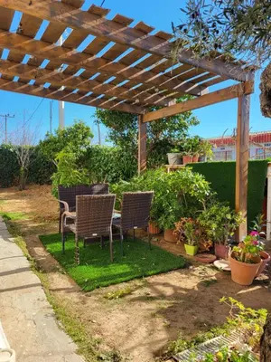 a patio with chairs and a table under a wooden pergola at Maria guesthouse in Spáta