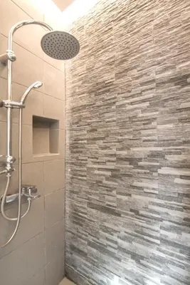 a bathroom with a shower with a stone wall at Luxury Haven in the most ideal area of Athens in Athens