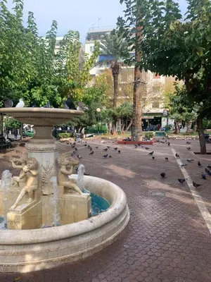 a fountain in a park with birds flying around it at ARIS- Queen suite on the boulevard in Athens