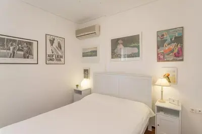 a white bedroom with a bed and pictures on the wall at Stylish Apartment in the Heart of Nea Smyrni in Athens