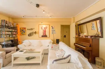 a living room with a white couch and a piano at Stylish Apartment in the Heart of Nea Smyrni in Athens