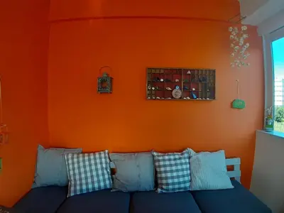 an orange wall with a couch in a living room at Cozy maisonette in Athinaiki Riviera of Palaio Faliro in Athens