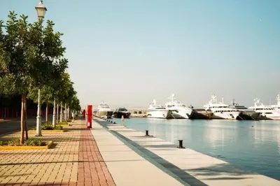 a walkway next to a harbor with boats in the water at Cozy maisonette in Athinaiki Riviera of Palaio Faliro in Athens