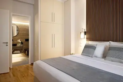 a bedroom with a large white bed and a bathroom at Acropolis Museum Central Suite in Athens