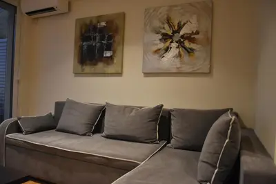 a couch in a living room with two paintings on the wall at Peaceful Retreat in Kolonaki in Athens
