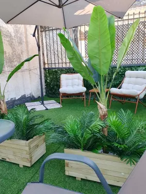 a patio with two chairs and an umbrella and plants at AIOLOS Rooftop suite centre GLYFADA in Athens