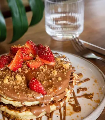 a stack of pancakes with strawberries on a plate at L'Avventura Suites in Athens