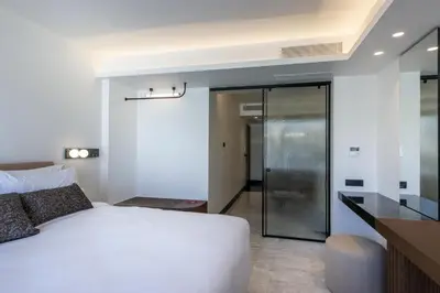 a bedroom with a white bed and a sliding glass door at L'Avventura Suites in Athens