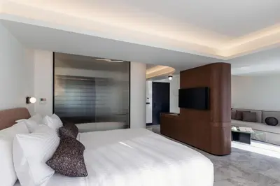 a bedroom with a large white bed with a flat screen tv at L'Avventura Suites in Athens