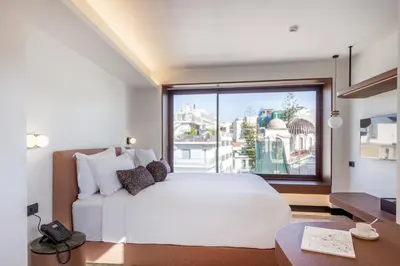 a bedroom with a white bed and a large window at L'Avventura Suites in Athens