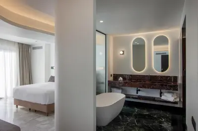 a bedroom with a bed and a tub and a mirror at L'Avventura Suites in Athens