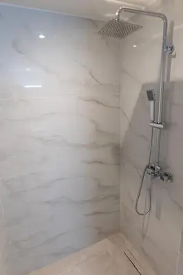a bathroom with a shower with white marble walls at A Lux, Athens center, Syntagma! Work or Play in Athens