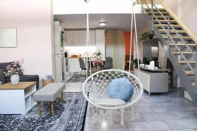 a living room with a chair and a staircase at New house in Piraeus in Piraeus