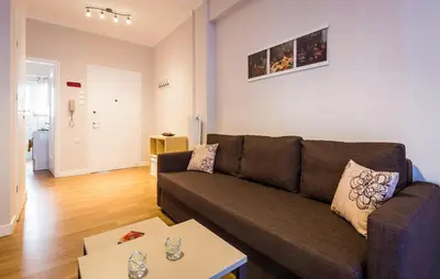 a living room with a brown couch and a table at YOUR BRAND NEW Awesome Acropolis Home in Athens