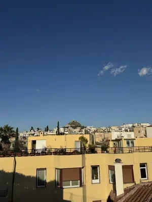 a view of a building with mountains in the background at Cozy Apartment with Acropolis View Rooftop Access in Athens