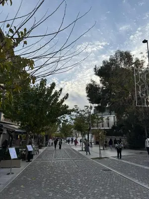 a cobblestone street with people walking on it at Cozy Apartment with Acropolis View Rooftop Access in Athens