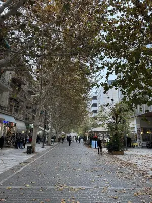 a tree lined street with people walking down it at Cozy Apartment with Acropolis View Rooftop Access in Athens