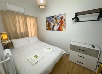 a bedroom with a white bed and a painting on the wall at Koukaki Athens Cozy Home in Athens