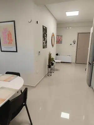 an empty room with white floors and tables and chairs at Ein Appartement zum wohlfühlen in Anavissos
