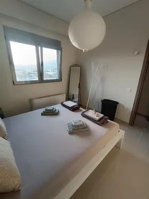a bedroom with a large white bed with a mirror at Ein Appartement zum wohlfühlen in Anavissos