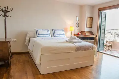 a white bedroom with a large bed with blue pillows at Anafiotika FOS Cycladic Home! in Athens