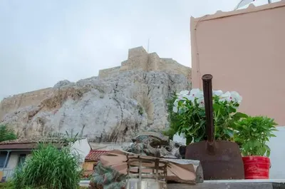 a building with flowers and a mountain in the background at Anafiotika FOS Cycladic Home! in Athens
