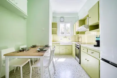 a kitchen with a wooden table and white cabinets at Spacious 3 Bedroom Flat at Metro in Athens