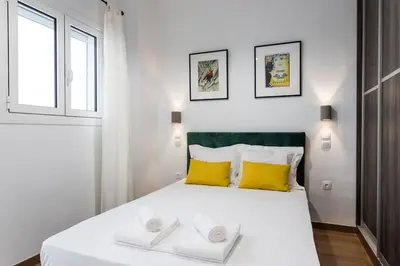 a bedroom with a large white bed with yellow pillows at Bohemian Chic in the Heart of Athens in Athens