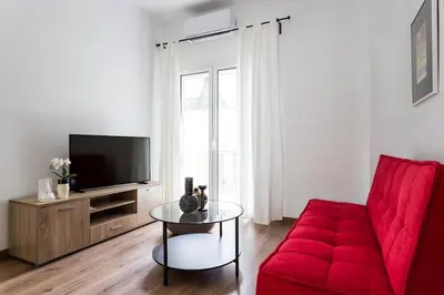 a living room with a red couch and a tv at Bohemian Chic in the Heart of Athens in Athens