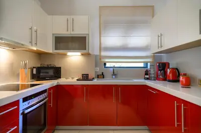 a kitchen with red cabinets and a white counter top at Athenian Riviera Prestige 2 bedroom in Athens