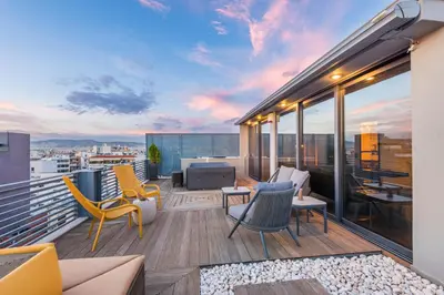 a balcony with chairs and tables on a building at Acropolis View Luxe Penthouse with Outdoor Terrace HotTub in Athens