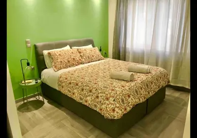 a green bedroom with a bed with two pillows at Agatha-2 in Piraeus
