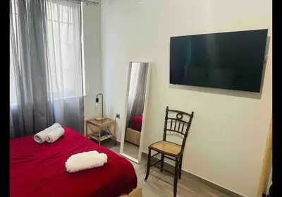 a bedroom with a red bed with a chair and a flat screen tv at Agatha-3 in Piraeus