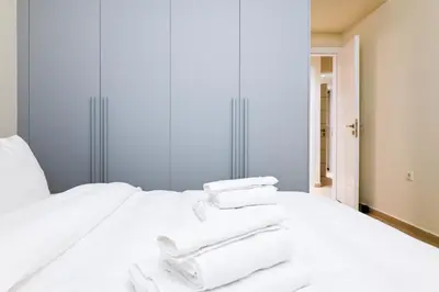 a white bed with towels stacked on top of it at Sophisticated Living ,Balcony & Stunning Interior in Athens