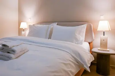 a white bed with white sheets and pillows and two lamps at Refined Kolonaki Stay ,Private Patio & Stylish Comfort in Athens