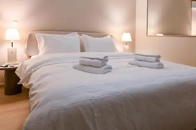 a large white bed with three towels on it at Refined Kolonaki Stay ,Private Patio & Stylish Comfort in Athens