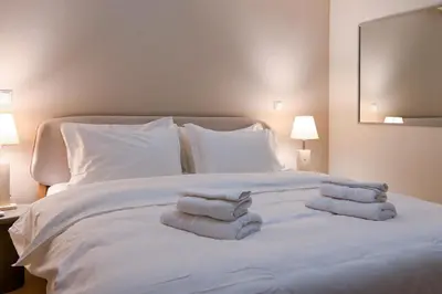 a large white bed with three folded towels on it at Refined Kolonaki Stay ,Private Patio & Stylish Comfort in Athens
