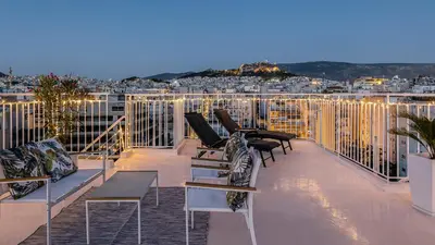 a balcony with chairs and tables on top of a building at Rooftops of Athens - Vathi Studio Jacuzzi & View in Athens