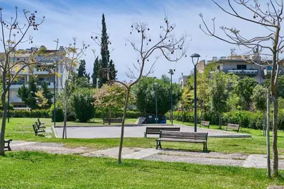 a park with benches and trees and buildings at Elegant family apartment with marvelous garden in Athens
