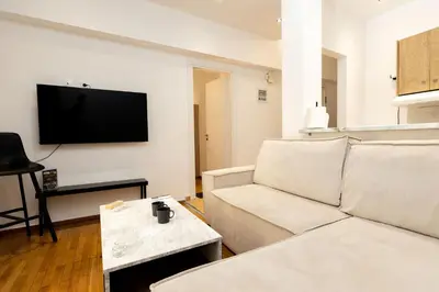 a living room with a white couch and a flat screen tv at Nova Domo in Athens