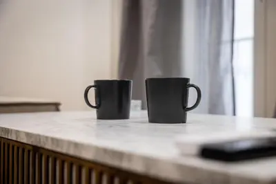 two black coffee mugs sitting on top of a counter at Nova Domo in Athens