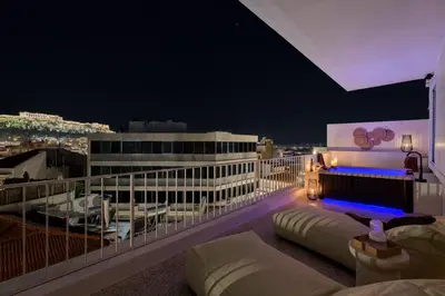 a balcony with a view of a city at night at Acropolis Penthouse Plunge Pool in Athens